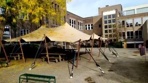 Meerdere zandkleurige stretchtenten opgesteld op het binnenplein van het Christelijk Lyceum in Haarlem voor een feestelijk schoolevenement