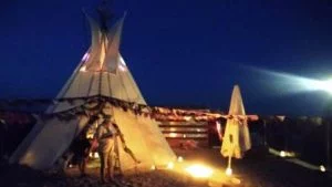 Exclusieve tipi verhuur voor een strandfeest in Amsterdam: sfeervol verlichte tipi op het zand van strand IJburg tijdens de avonduren