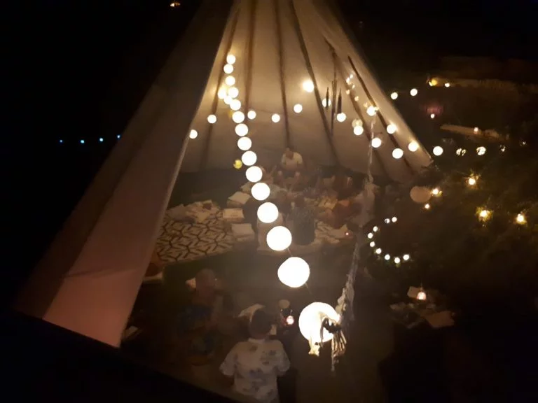 Groep mensen tijdens een verjaardagsfeest in een gezellig ingerichte tipi.