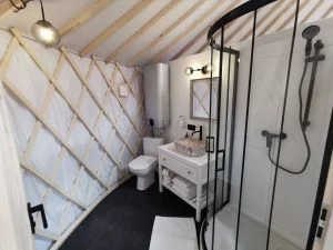 Luxe sanitair-unit in de yurt met een moderne douche, wastafel en toilet, perfect voor permanente bewoning als tiny house