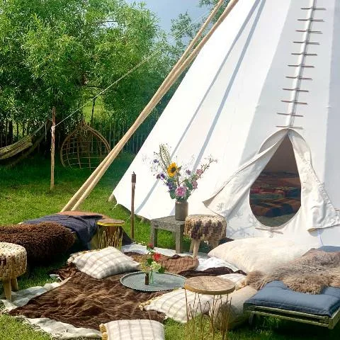 luxe tipi tent 7 meter in de tuin met schapenvachten, kussens en bloemen
